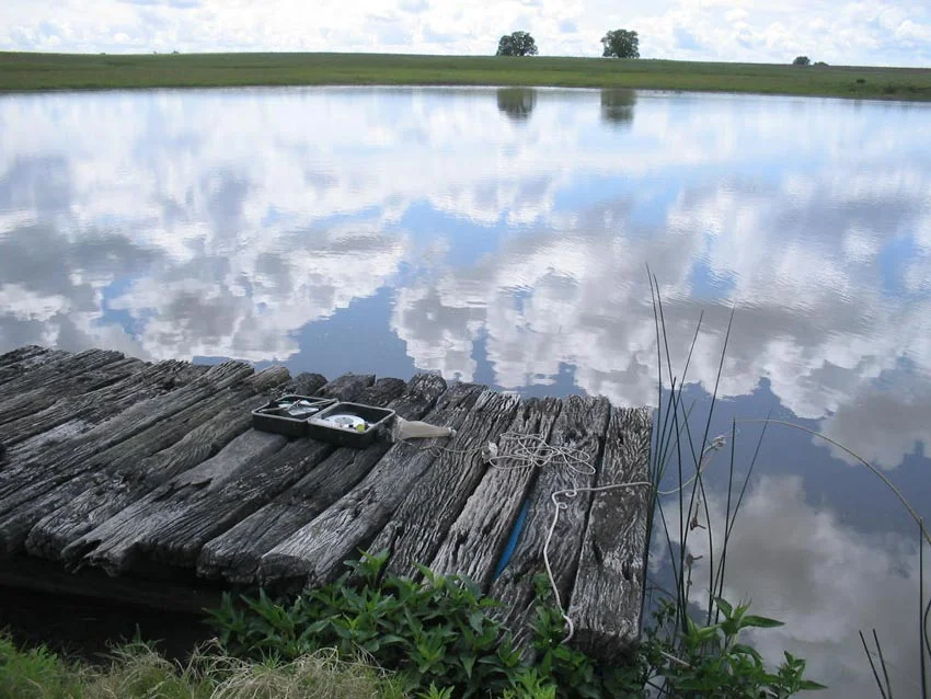 Muelle de madera sobre una laguna que refleja el cielo
